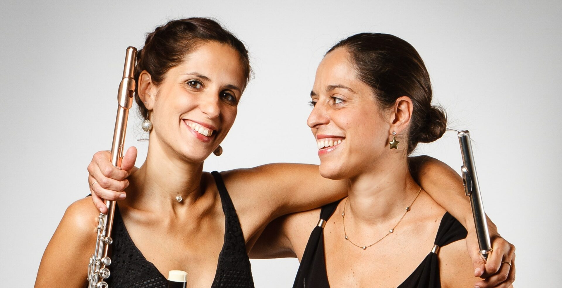 Deux femmes sourient en se tenant par les épaules avec des flûtes à la main.